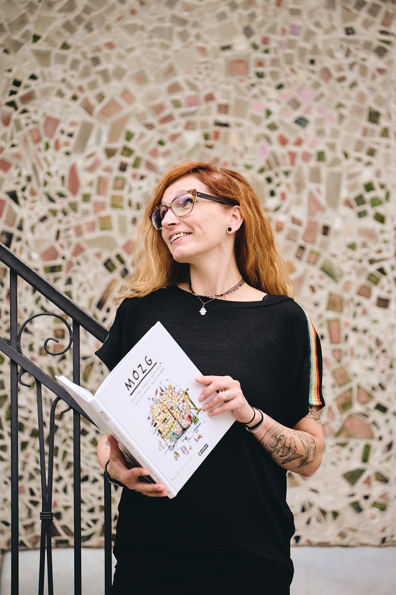 Joanna Krzemińska z otwartą książką na tle mozaiki